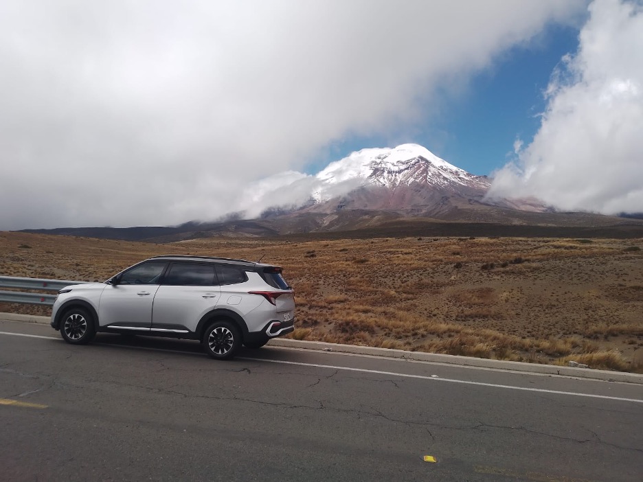 A white SUV is parked on the side of a paved road, with a vast, dry landscape